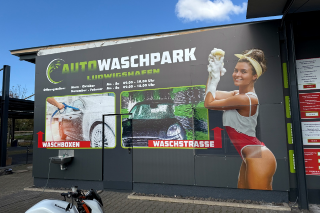 Große Werbetafel eines Autowaschparks in Ludwigshafen mit Waschmotiven und einer Frau mit Schaumhandschuh.