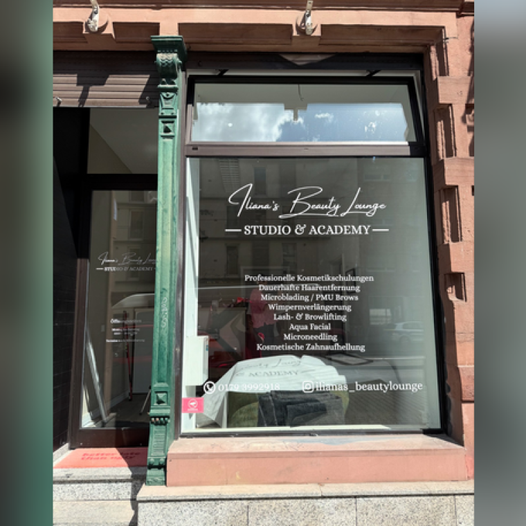 Schaufenster eines Beauty-Studios mit aufgedrucktem Logo und Behandlungsangeboten.