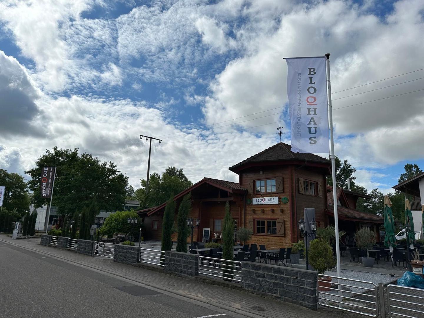 Holzgebäude eines Restaurants mit Fahnen vor einer Straße unter wolkigem Himmel