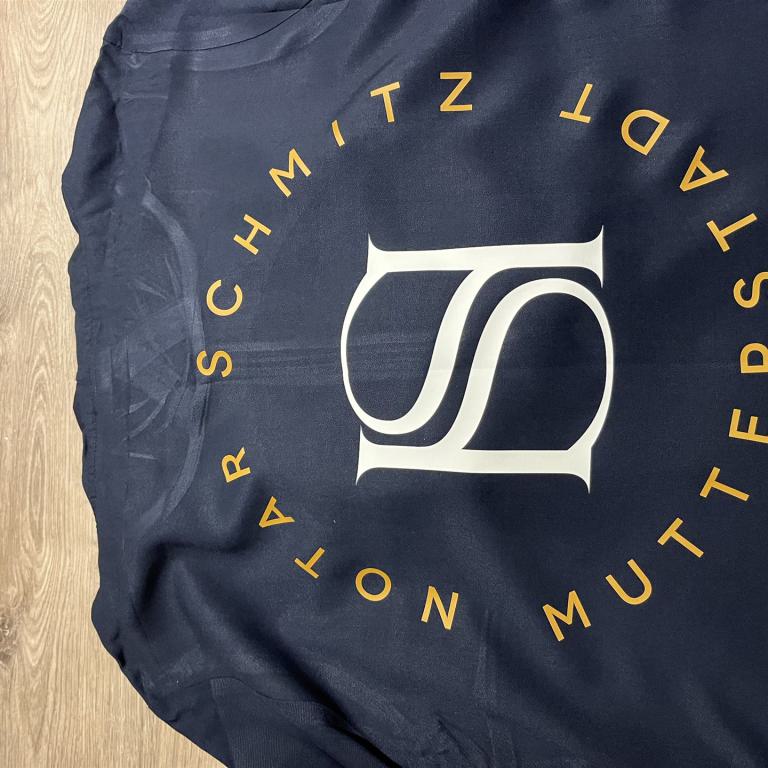 Dunkles T-Shirt mit rundem Schriftzug und großem weißen Monogramm in der Mitte.