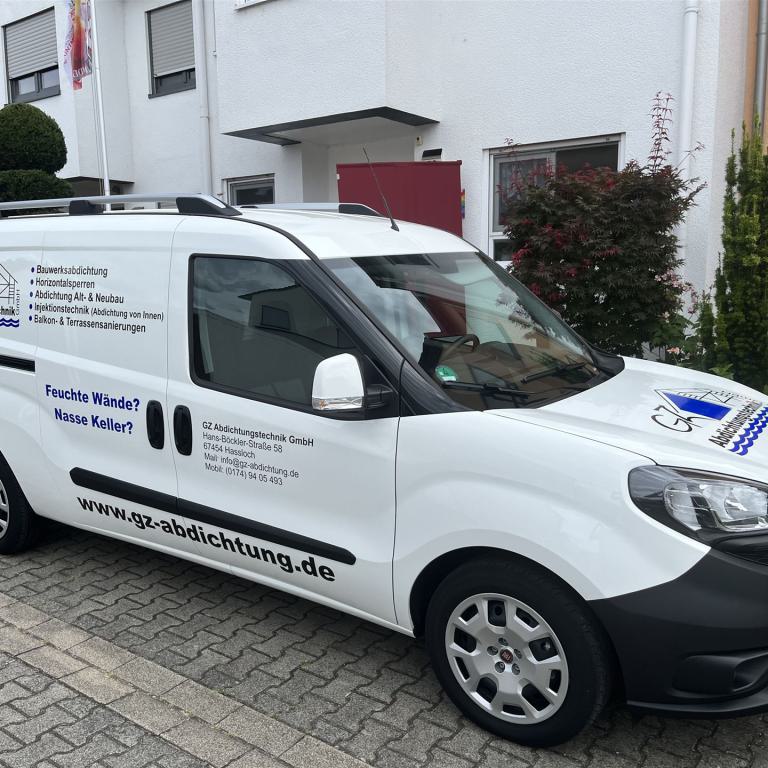 Weißer Firmenwagen eines Abdichtungstechnik-Unternehmens vor einem Wohnhaus geparkt.