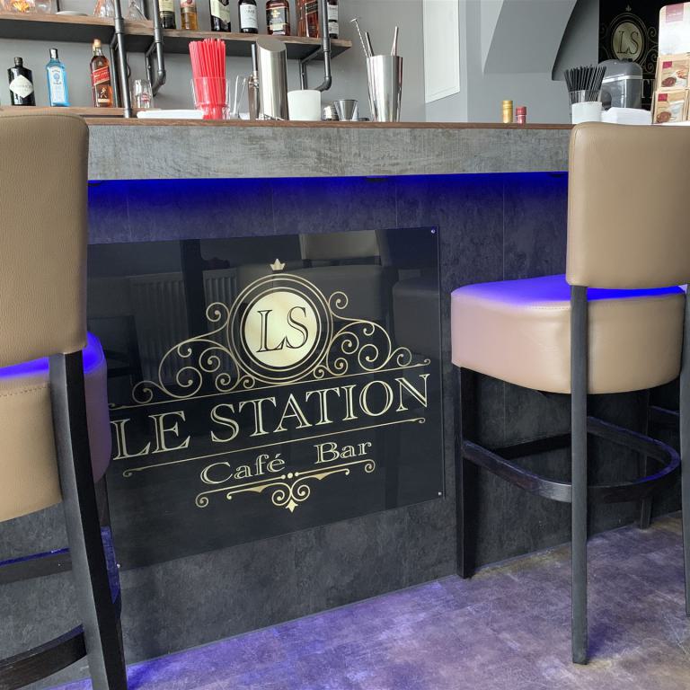 Barbereich eines Cafés mit hohen beige gepolsterten Stühlen und blauem Licht unter dem Tresen.