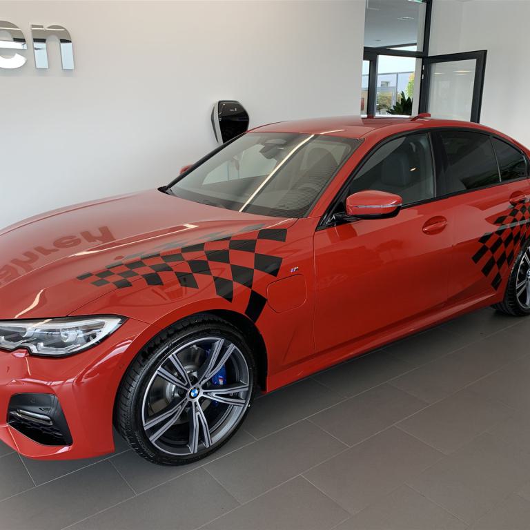 Rote BMW Limousine mit schwarzem Karomuster in einem hellen Ausstellungsraum.