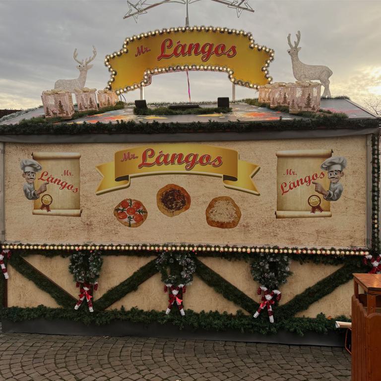 Dekorierter Imbissstand mit der Aufschrift Mr. Lángos auf einem winterlich geschmückten Markt.